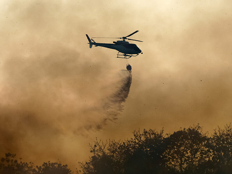 Helicopter dumping water on bushfire